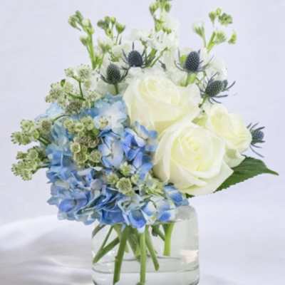 Blue hydrangeas and white roses in a clear glass vase