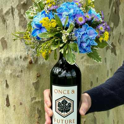 Bouquet of blue, purple, and yellow flowers in a wine bottle vase
