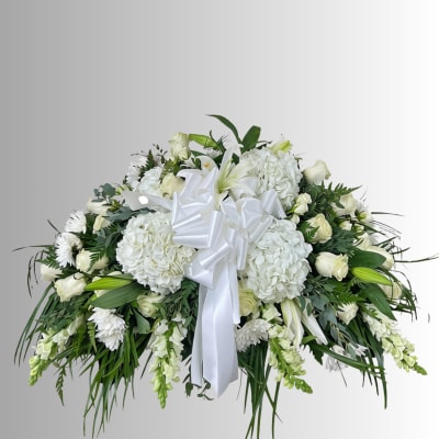 White floral spray with lilies, roses, and hydrangeas tied with a white ribbon
