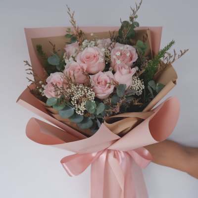Pink rose bouquet wrapped in blush paper with a satin ribbon