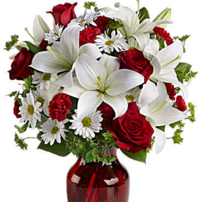 Red roses and white lilies arranged in a red glass vase