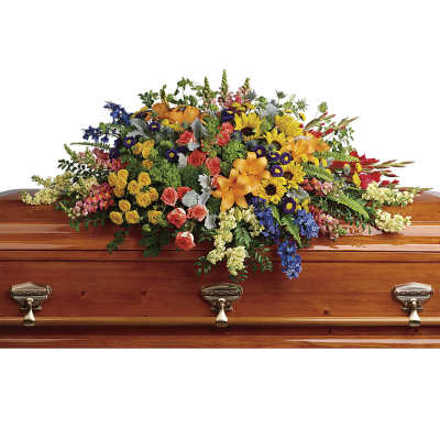 Colorful floral casket spray with roses, lilies, sunflowers, and blue blooms