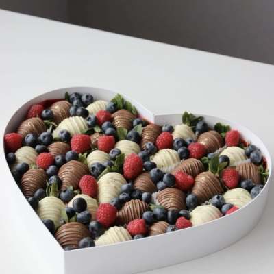 Heart-shaped box filled with chocolate-covered strawberries, raspberries, and blueberries