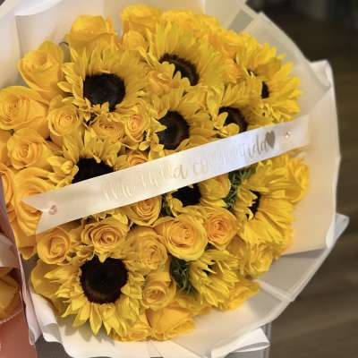 Bouquet of yellow roses and sunflowers wrapped in white paper