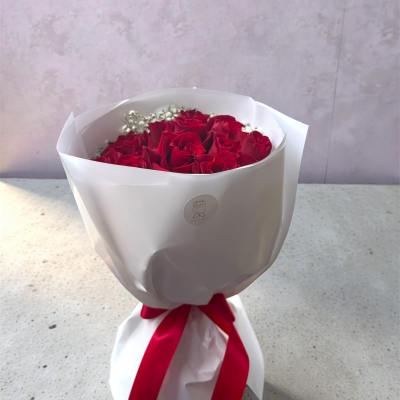 Bouquet of red roses wrapped in white paper with a red ribbon