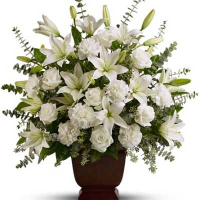 White lilies and roses arranged in a dark urn vase