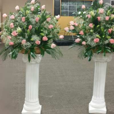 Two pink rose arrangements on white pedestal stands