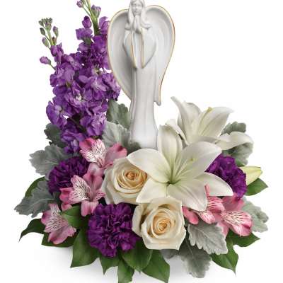 White angel figurine surrounded by purple, pink, and white flowers