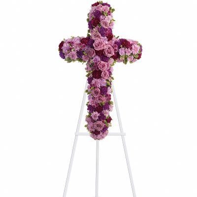 Cross-shaped floral tribute on a white easel with pink and purple flowers
