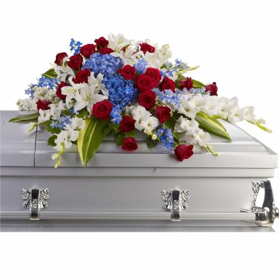 Red roses, white lilies, and blue flowers arranged on a silver casket