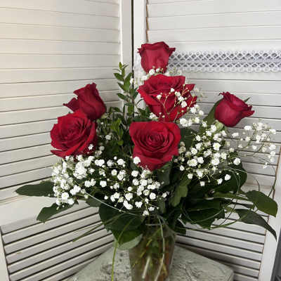Red roses with baby's breath in a clear glass vase