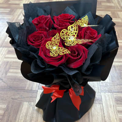 Bouquet of red roses wrapped in black paper with gold butterfly accents