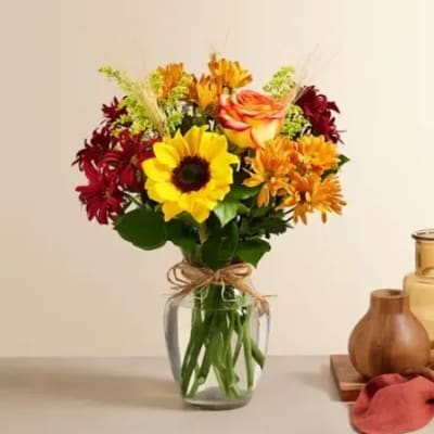 Mixed bouquet of sunflowers, roses, and chrysanthemums in a glass vase