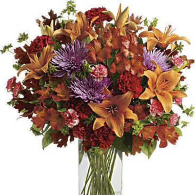 Autumn bouquet of lilies, chrysanthemums, and carnations in a clear glass vase