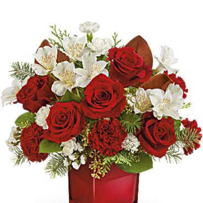 Red roses and white flowers arranged in a red glass vase