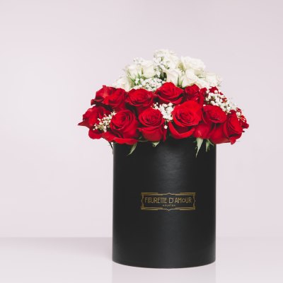 Red and white roses arranged in a black hat box