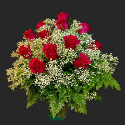 Red roses arranged with white filler flowers in a glass vase