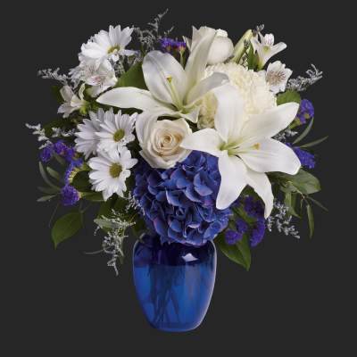 White lilies, daisies, and blue hydrangea in a blue vase