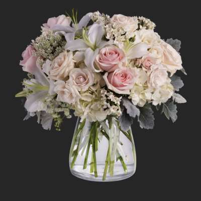 Pink and white roses with lilies in a clear glass vase
