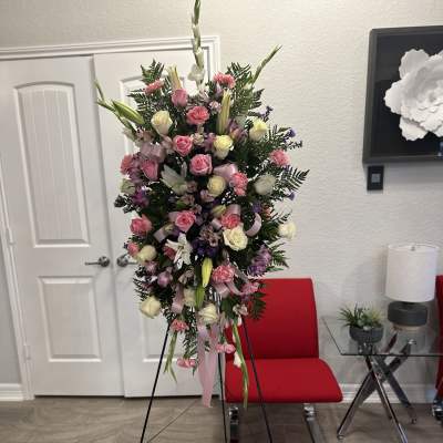 Tall pink and white standing spray of roses, lilies, and carnations on a metal easel
