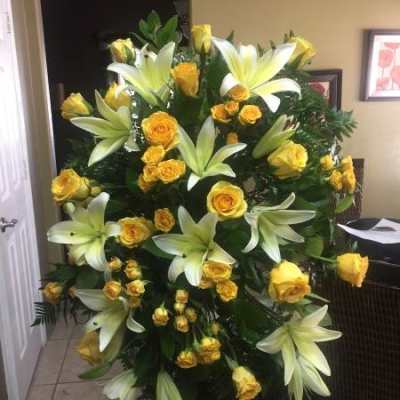 Tall standing spray of yellow roses and white lilies on an easel
