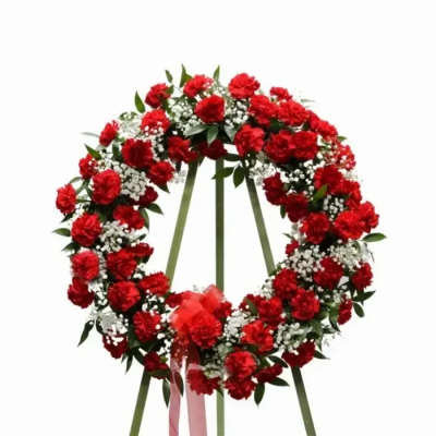 Red carnation funeral wreath with white filler flowers on a stand