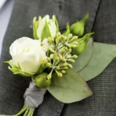 White boutonniere with green buds and leaves on a suit jacket