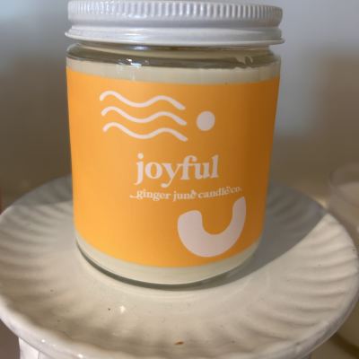 Glass jar candle with an orange label on a white surface