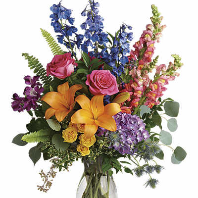 Colorful mixed bouquet in a clear glass vase with lilies, roses, and snapdragons