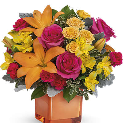 Bright bouquet of roses, lilies, and alstroemeria in an orange vase