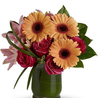 Pink roses and peach gerbera daisies in a green glass vase