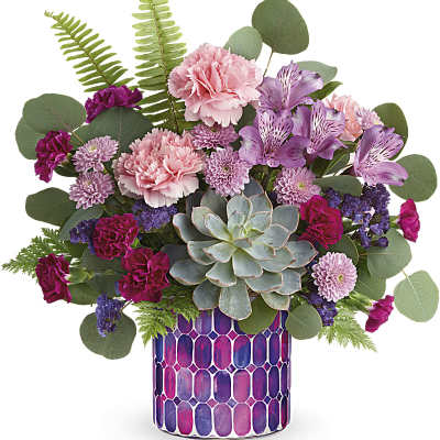 Pink and purple floral arrangement in a patterned vase with a succulent centerpiece