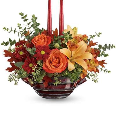 Autumn floral centerpiece with two red candles in a dark glass bowl