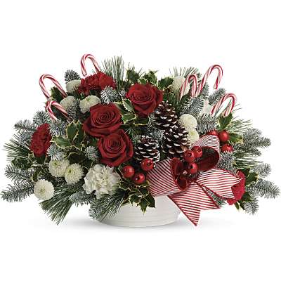 Christmas floral arrangement with red roses, pinecones, and candy canes in a white bowl