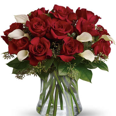 Red roses and white calla lilies in a clear glass vase