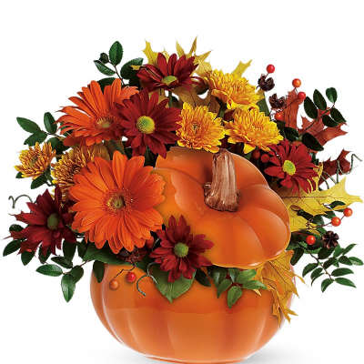 Autumn flower arrangement in a pumpkin-shaped vase with orange and red blooms