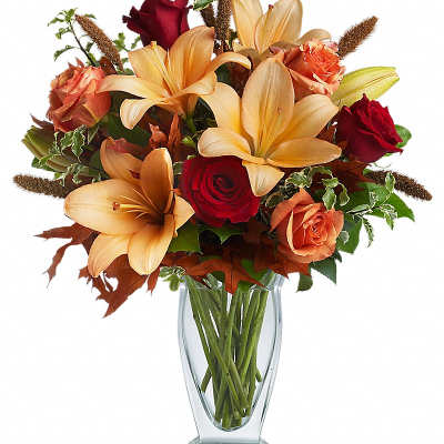 Bouquet of orange lilies and red roses in a clear glass vase