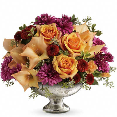 Orange roses and purple mums arranged in a silver pedestal vase