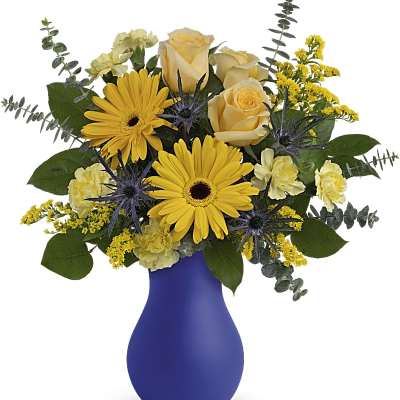 Yellow flowers in a blue vase with purple thistle accents