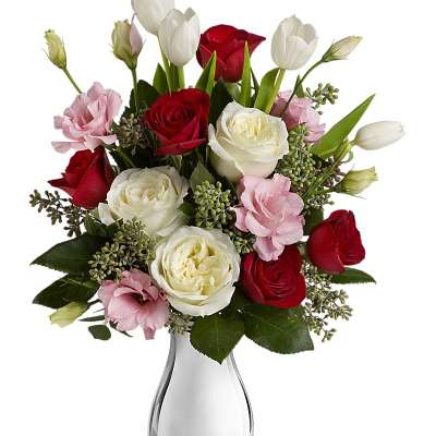 Bouquet of red and white roses with pink blooms in a clear glass vase