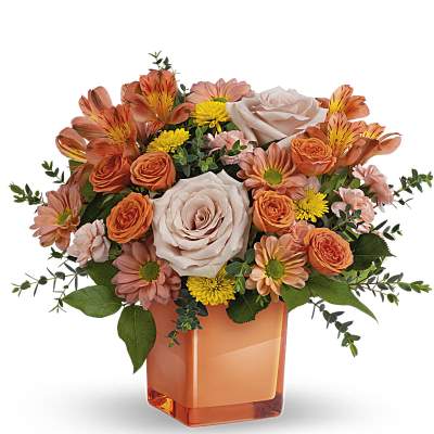 Orange and blush bouquet in a square orange vase