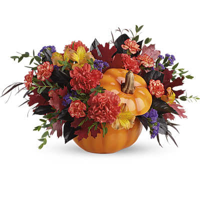 Autumn floral arrangement in a pumpkin container with orange and red blooms