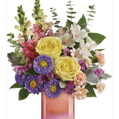 Mixed bouquet with yellow roses, purple daisies, and pink flowers in a pink glass vase