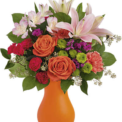 Orange vase with pink lilies, orange roses, and mixed flowers