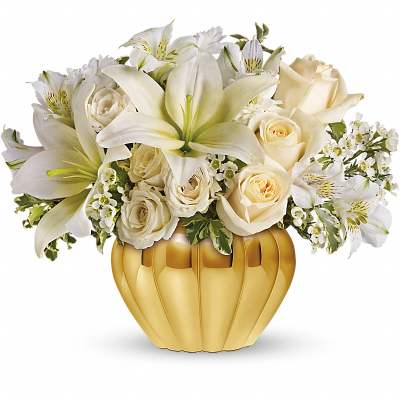 White lilies and roses arranged in a gold pumpkin vase