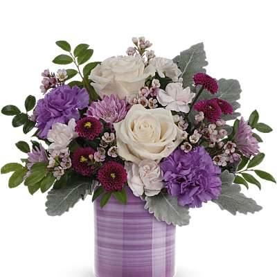 Purple and white floral arrangement in a lavender vase