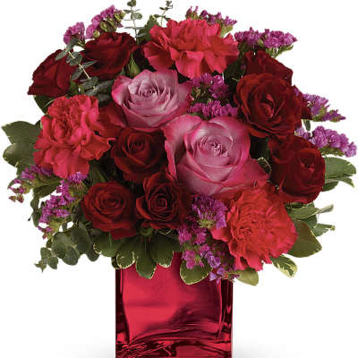 Bouquet of red and pink roses with carnations in a red glass vase