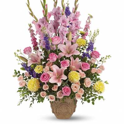 Tall floral arrangement with pink lilies, roses, and purple blooms in a decorative vase