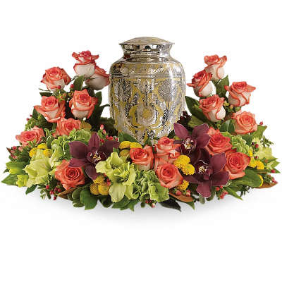 Floral urn arrangement with coral roses and dark orchids around a silver urn