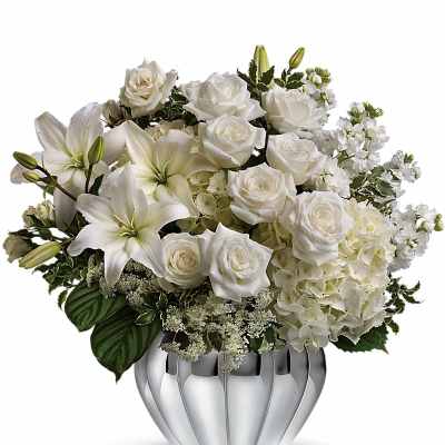 White roses and lilies arranged in a silver vase